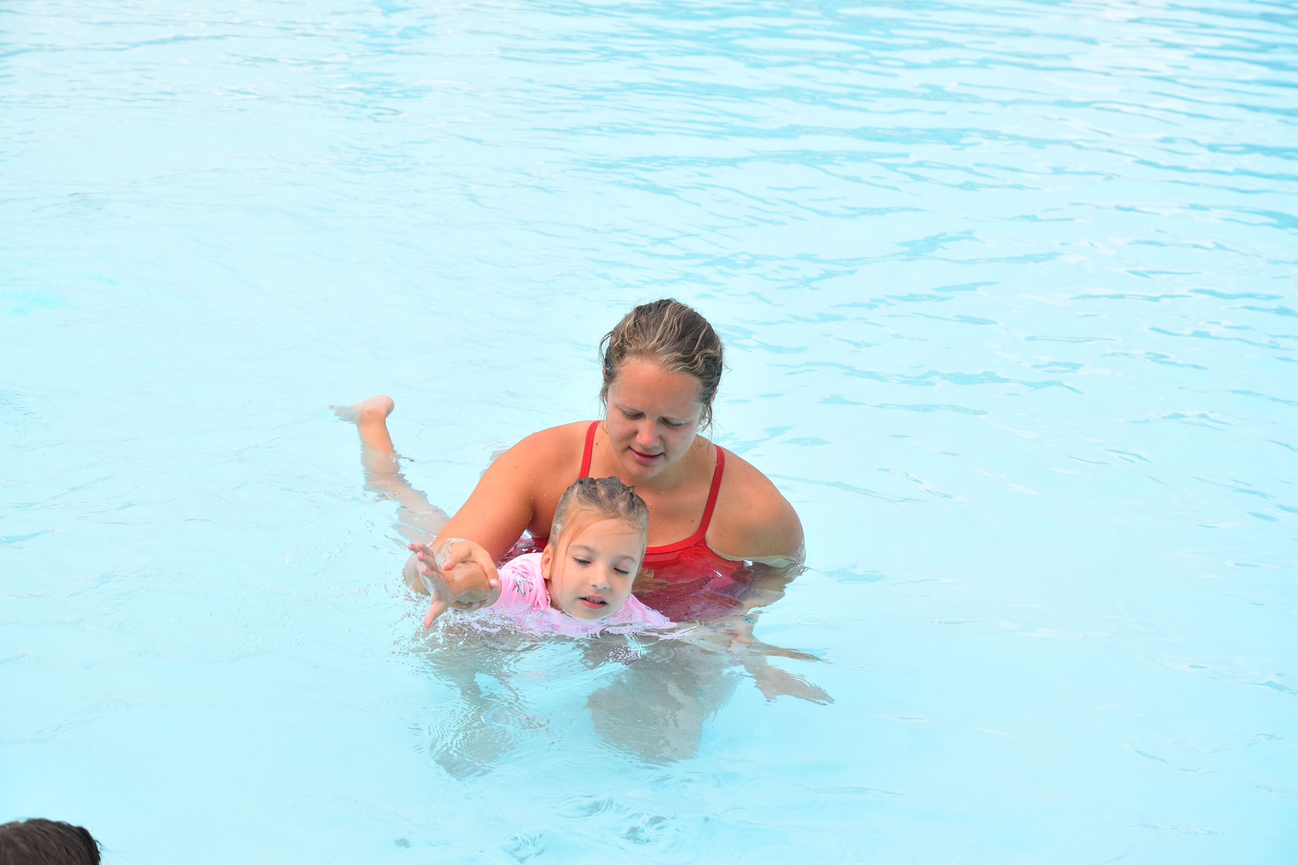 Lifeguard guiding girl in pink suit
